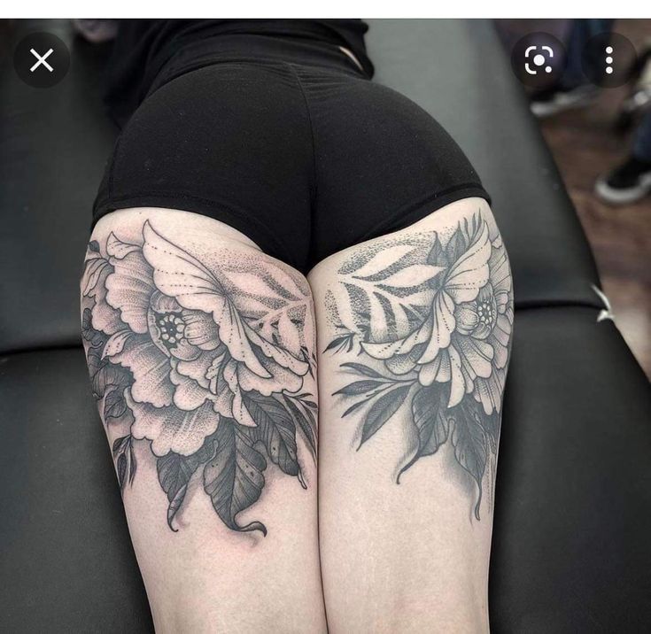 a woman's legs with flowers and leaves tattooed on her thigh, sitting on a couch