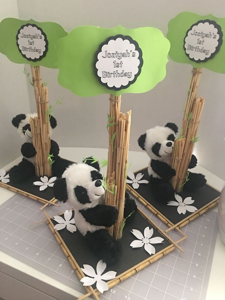 two panda bears sitting on top of black and white plates with bamboo sticks sticking out of them