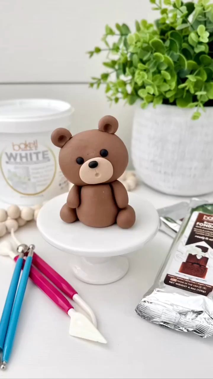 a small teddy bear sitting on top of a white plate next to some chocolates