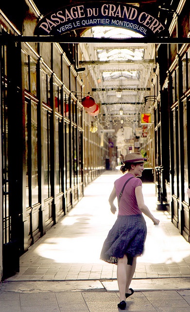 a woman is walking down the street in front of a sign that says passage du grand cer