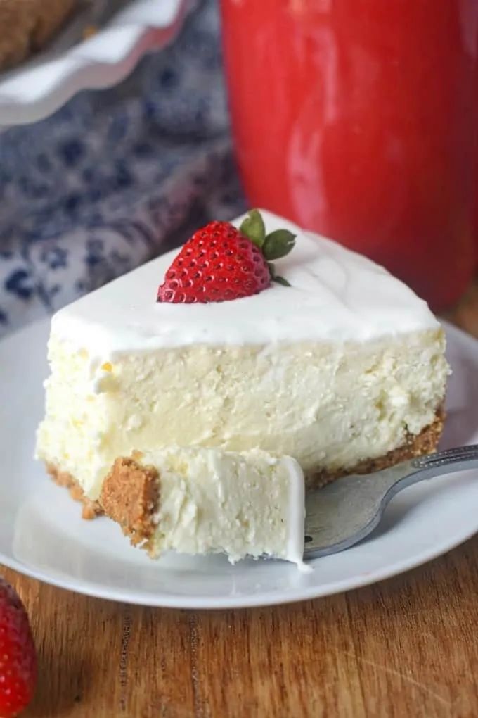 a piece of cheesecake on a white plate with strawberries