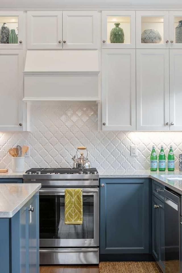 a kitchen with blue cabinets and white counter tops is pictured in this image, there are green vases on the shelves above the stove