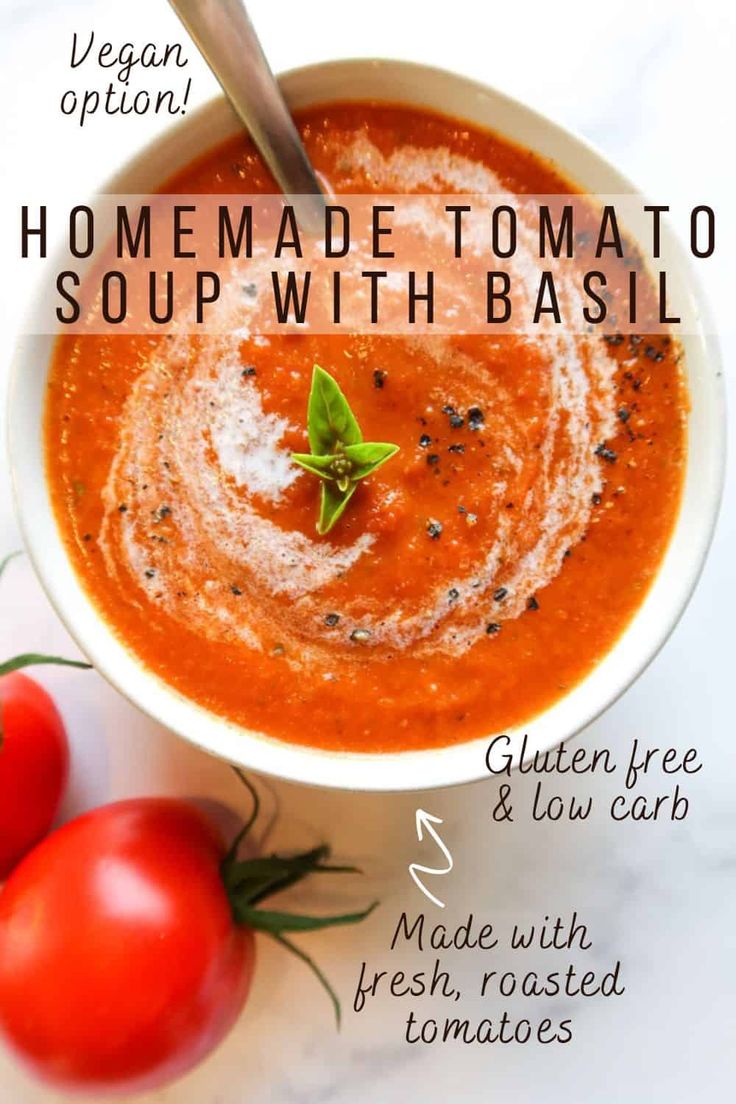 a bowl of homemade tomato soup with basil on the side and tomatoes next to it