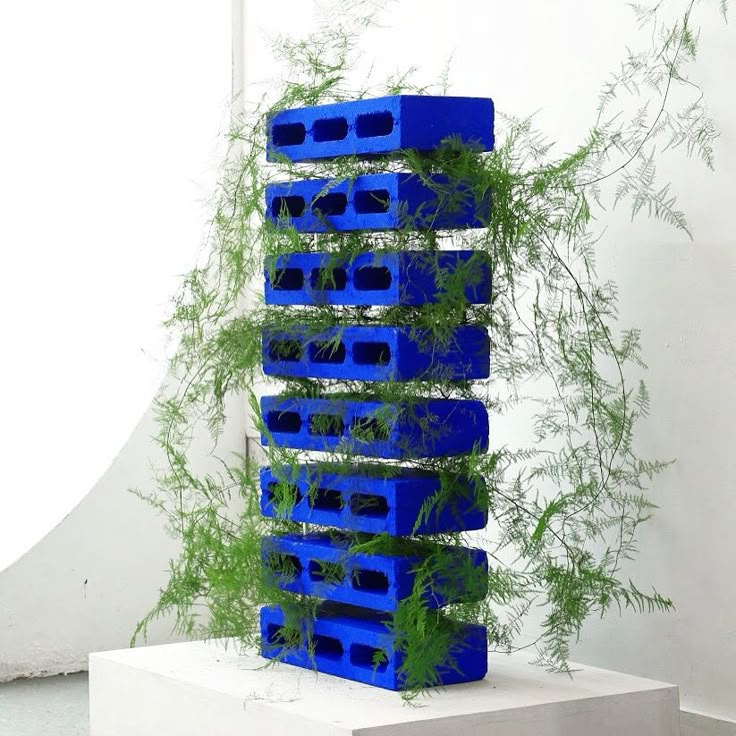 a sculpture made out of blue plastic crates with plants growing in them on top of it