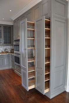 an empty kitchen with gray cabinets and wood floors