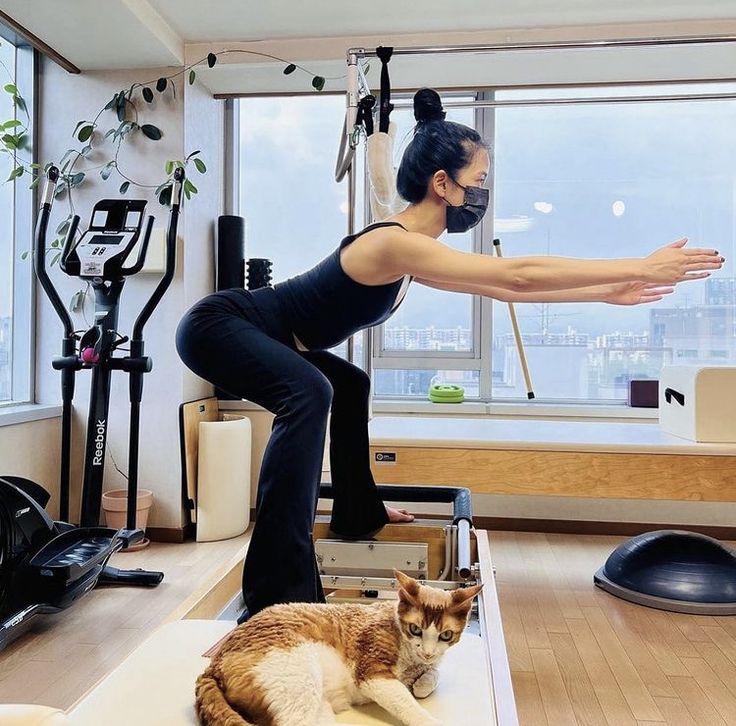 a woman is doing yoga with her cat on the floor in front of an exercise room