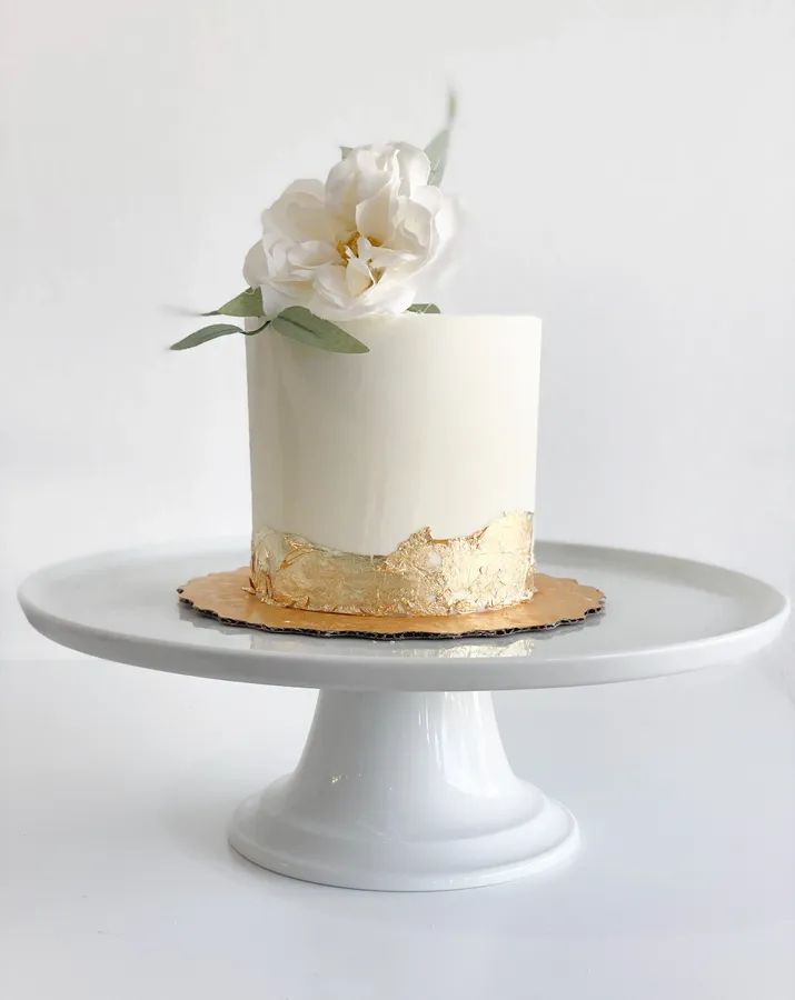 a white and gold cake with flowers on top