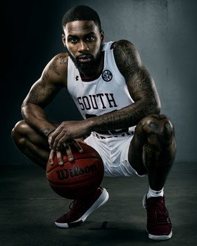 a basketball player is posing for a photo in his uniform and holding a ball with both hands