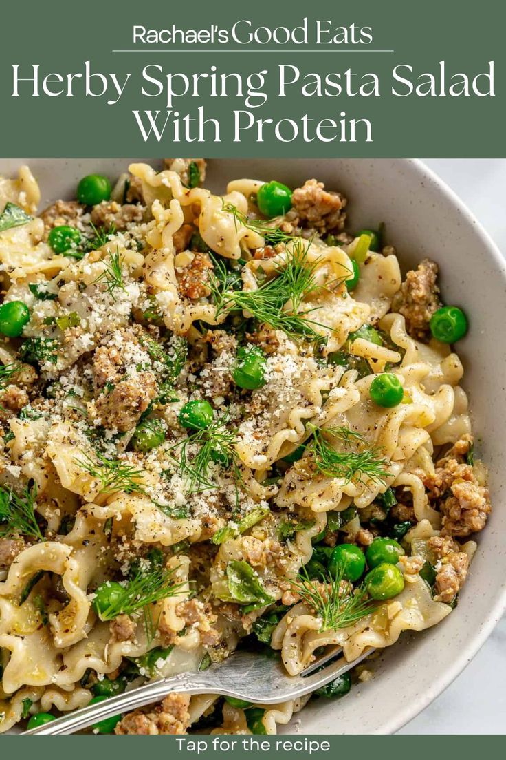 a white bowl filled with pasta and peas on top of a marble table next to a fork