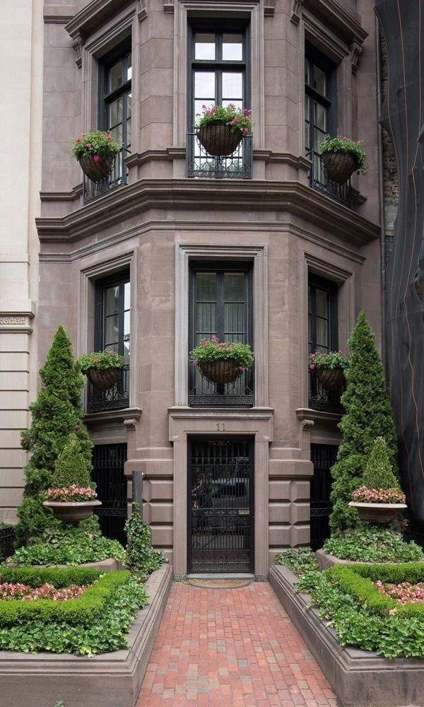 an apartment building with many plants and flowers in the window boxes on either side of the entrance