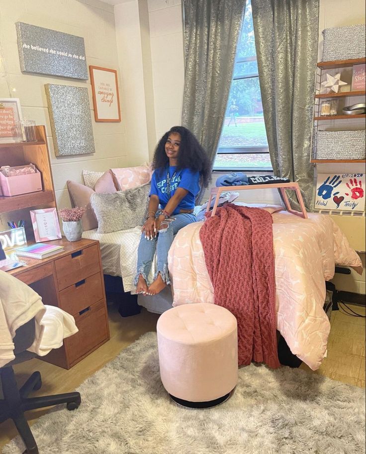 a woman sitting on top of a bed in a room with pink furniture and decor