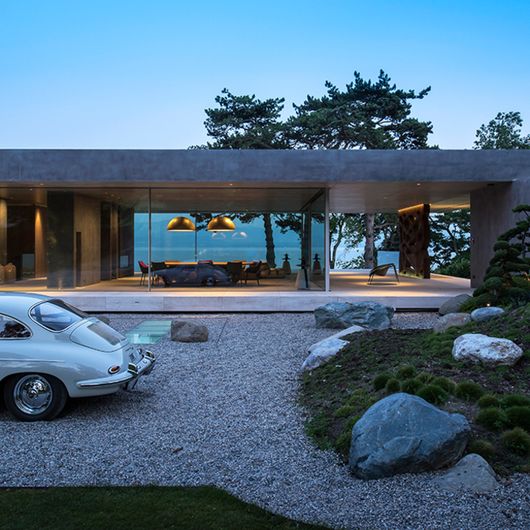 an old car is parked in front of a modern house