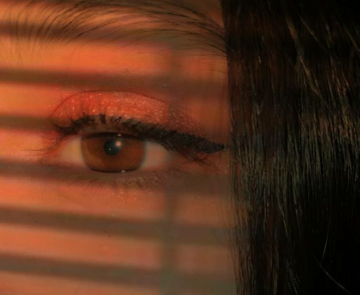 a woman's eye is seen through the blinds