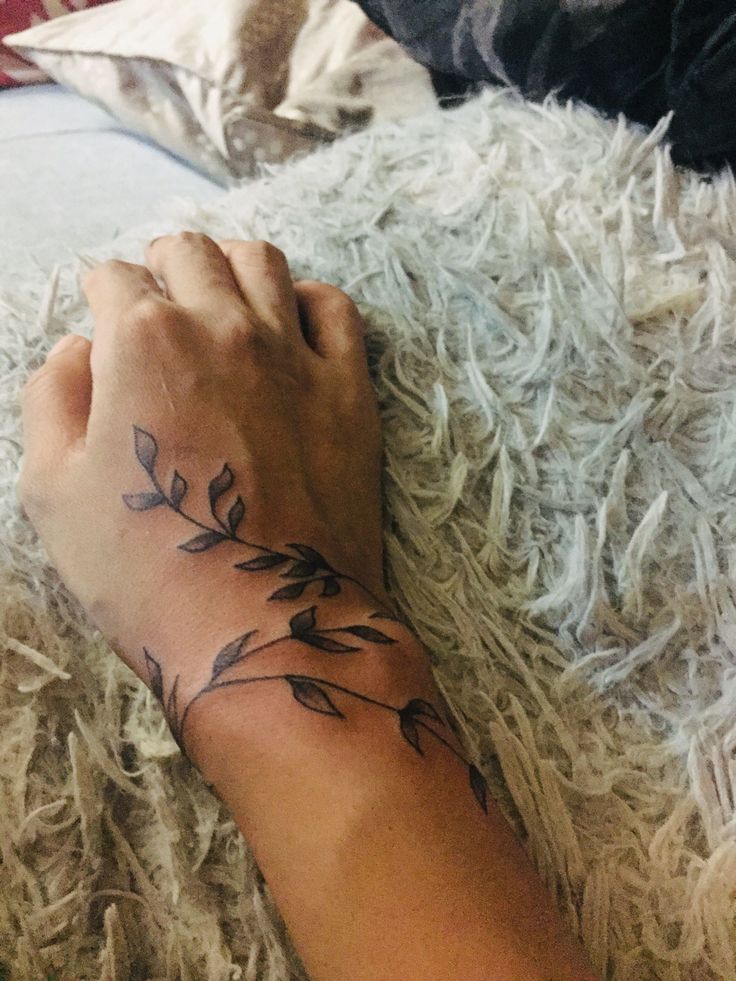 a woman's arm with a flower tattoo on it, resting on a fluffy white blanket