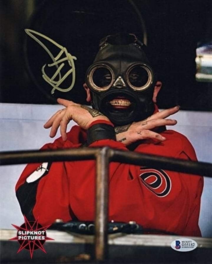 a man wearing a gas mask and holding his hands out to the side while sitting in a chair