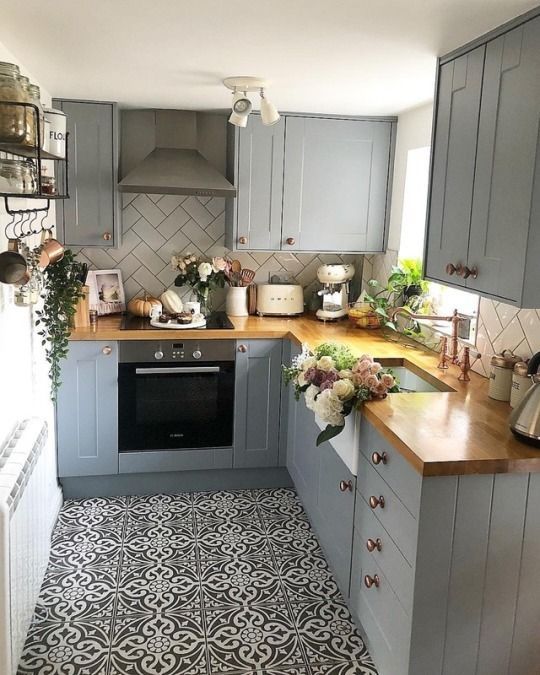 a kitchen with grey cabinets and wooden counter tops, an oven and sink are in the middle