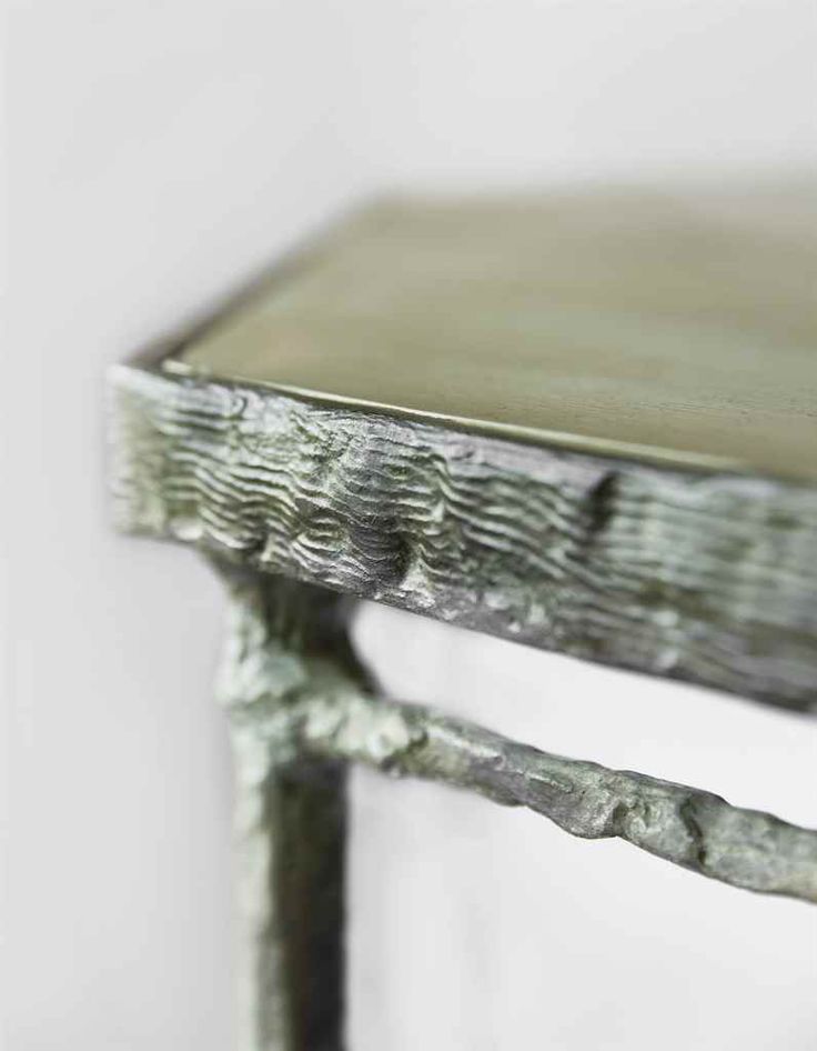 an old wooden table with metal legs and a green pattered finish on the top