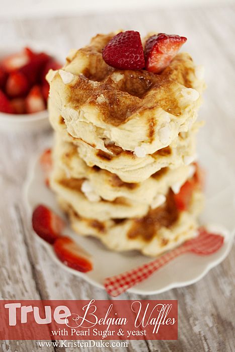 a stack of pancakes with strawberries on top and another plate in the foreground