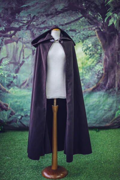 a cape on top of a mannequin head in front of a green background