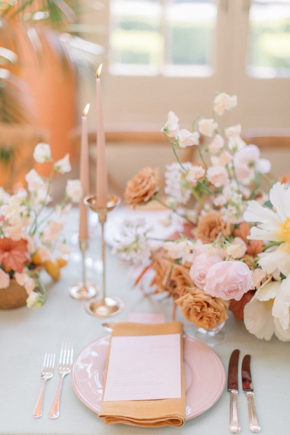 the table is set with pink and white flowers, silverware, and napkins