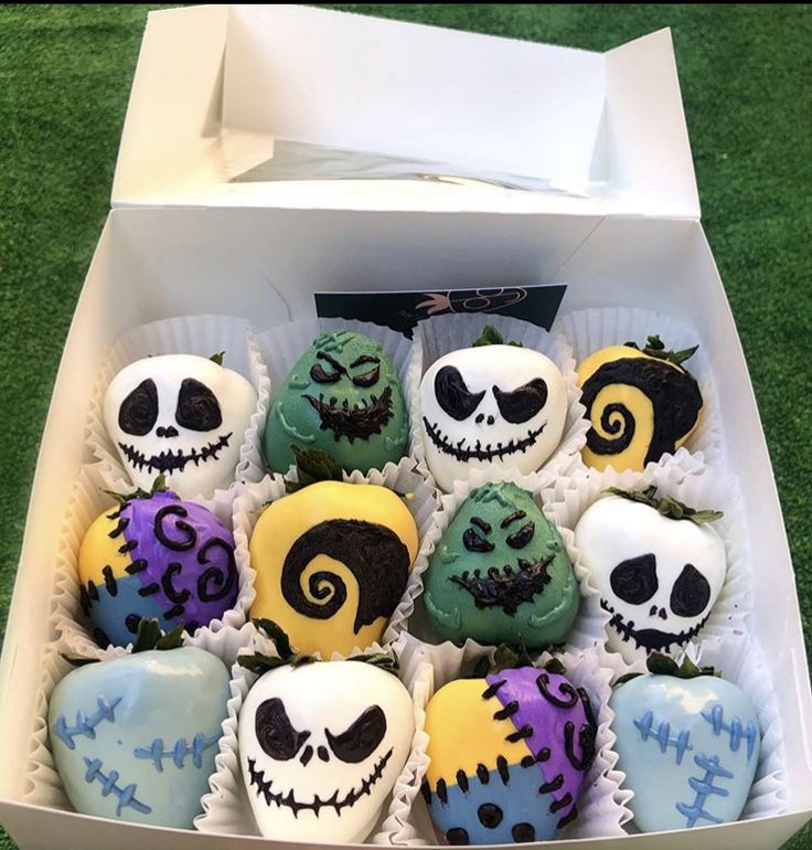 a box filled with halloween cupcakes sitting on top of a grass covered field