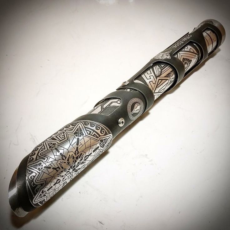 a pen with intricate designs on it sitting on a white surface, next to a lighter