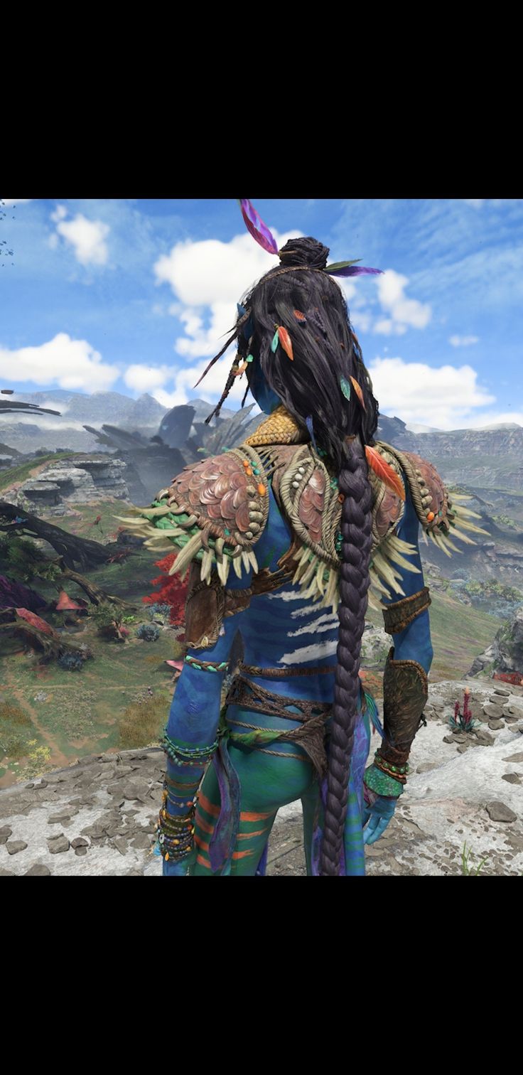 a person with long hair and dreadlocks standing on top of a hill in front of mountains