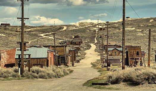 an old western town in the middle of nowhere, with telephone poles on either side