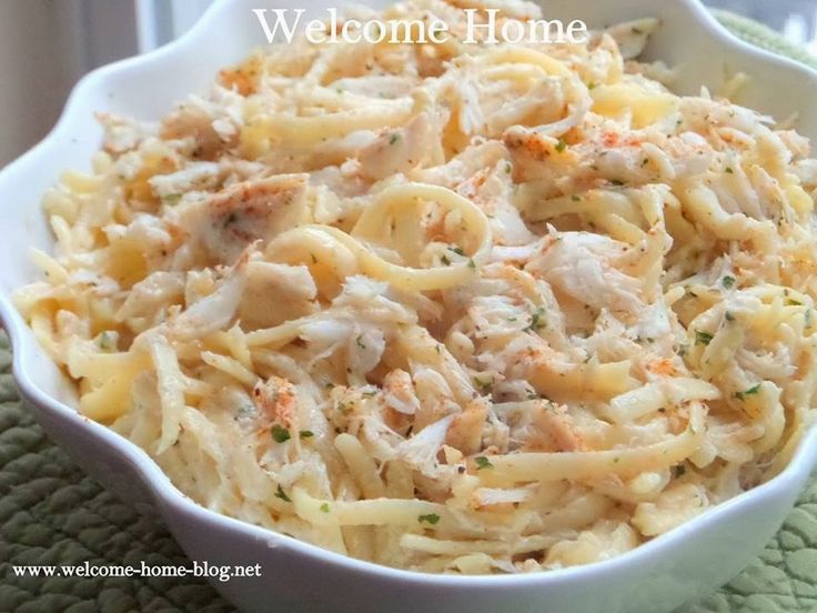 a white bowl filled with pasta and chicken on top of a green place mat next to a window