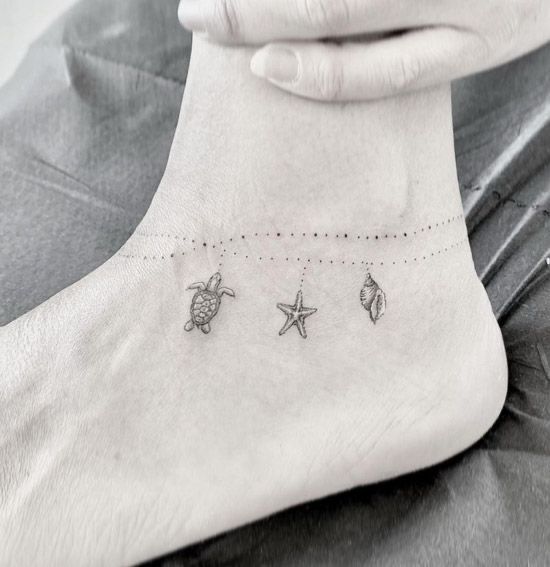 a woman's foot with three starfishs and sea shells on the ankle