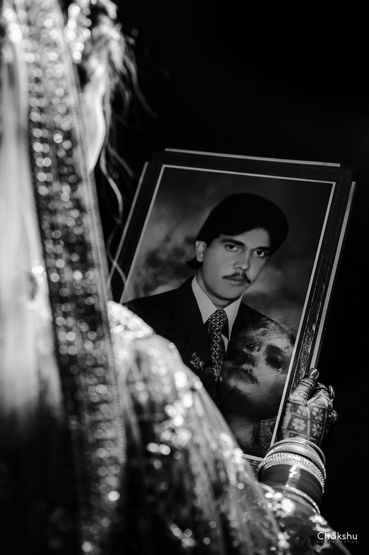 a black and white photo of a man holding a portrait