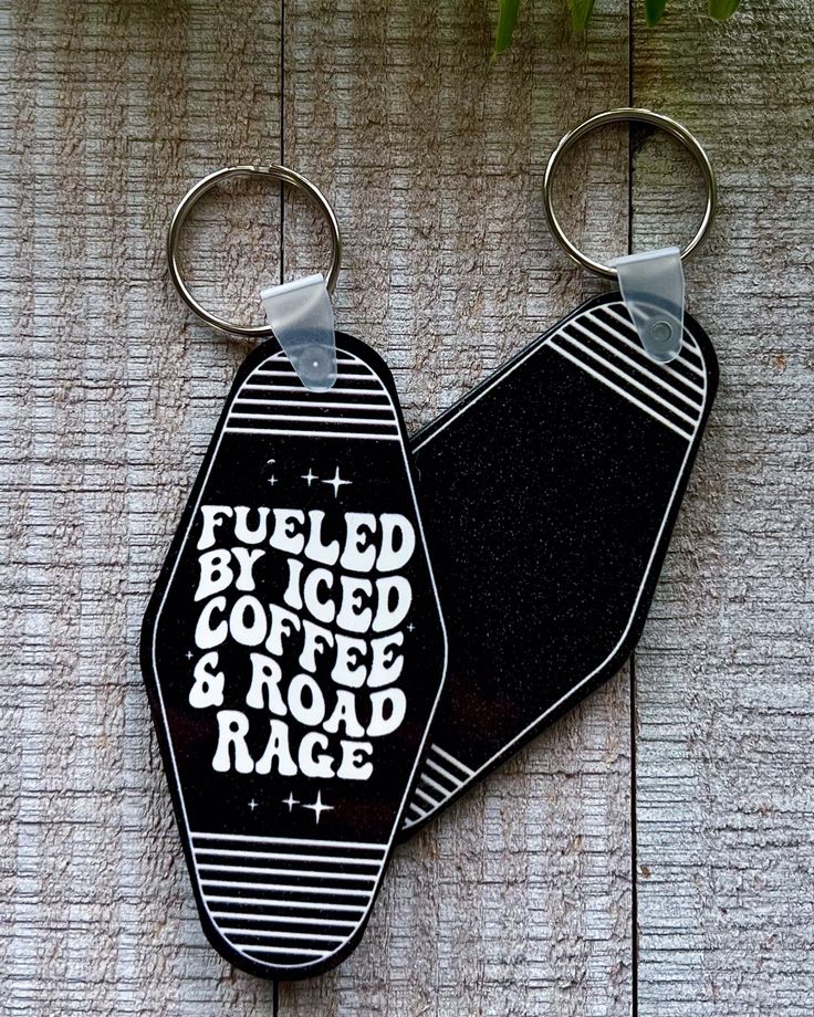 two black and white keychains with words on them