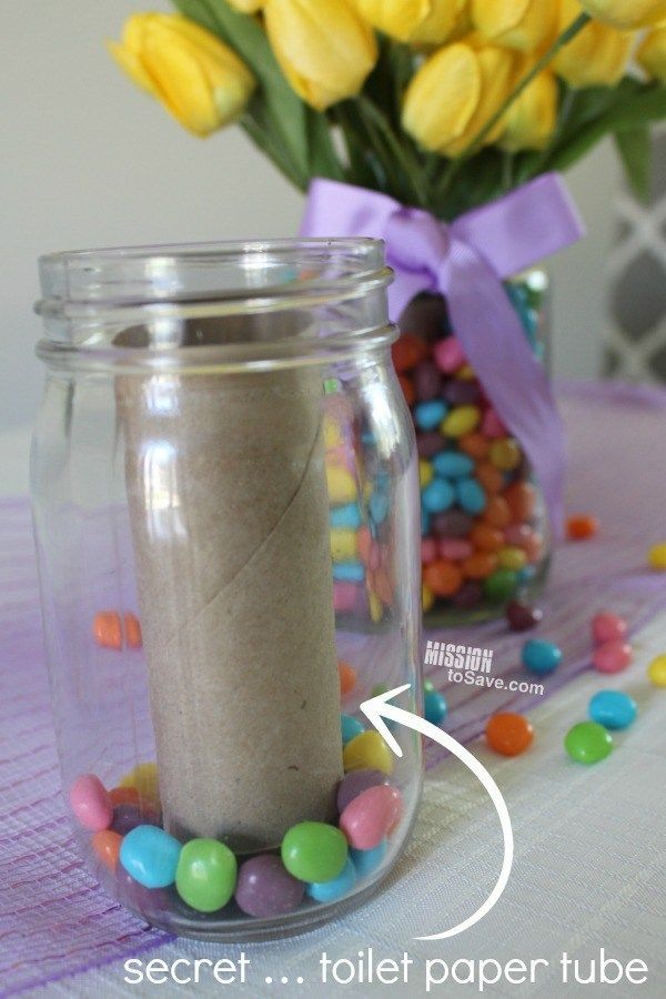 there is a jar with candy in it next to a vase filled with yellow tulips