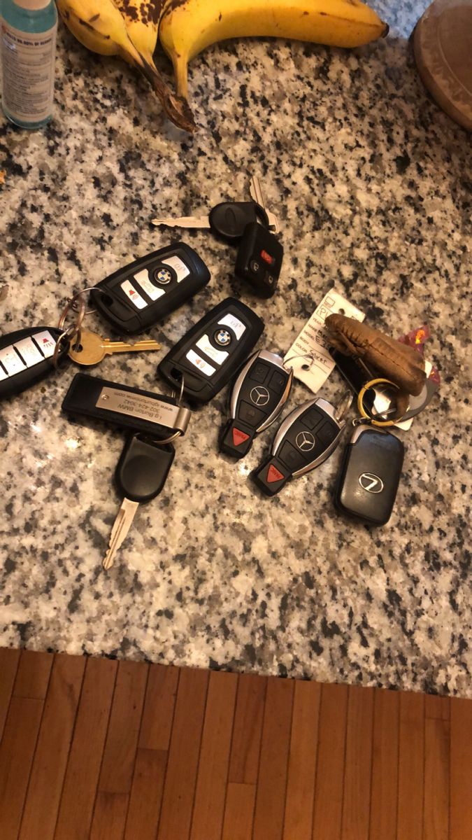 several car keys are laid out on a counter top next to bananas and other items