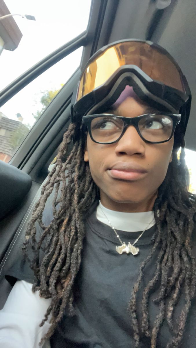 a woman with dreadlocks and goggles sitting in a car looking at the camera