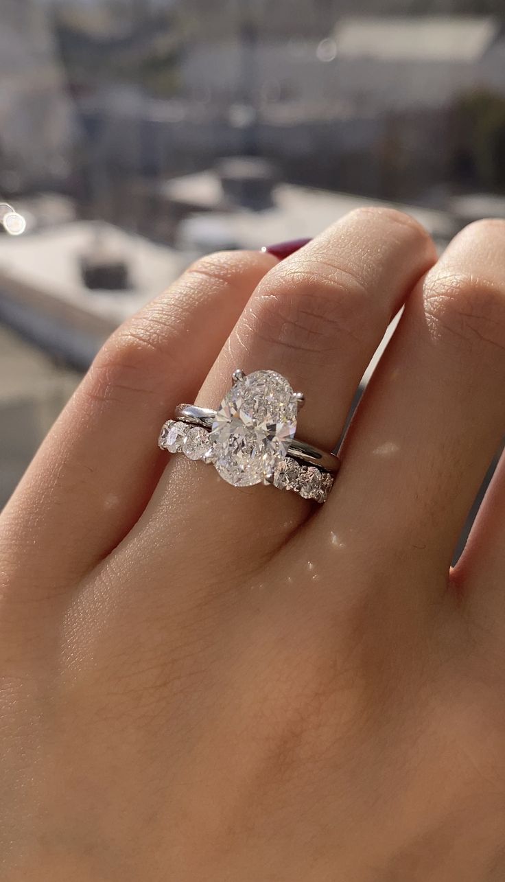 a woman's hand with a diamond ring on top of her finger, overlooking the city