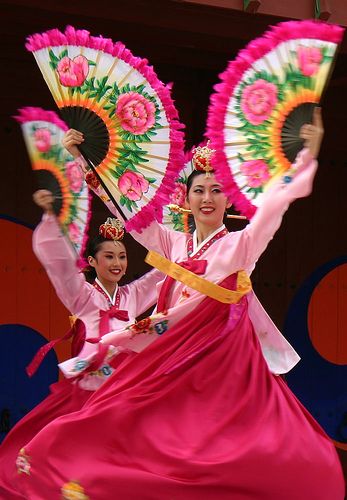 two women dressed in traditional chinese clothing holding parasols and dancing with each other