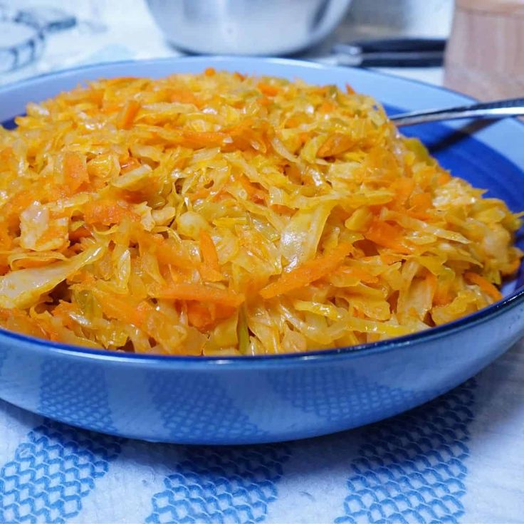 a blue bowl filled with shredded carrots on top of a white and blue table cloth