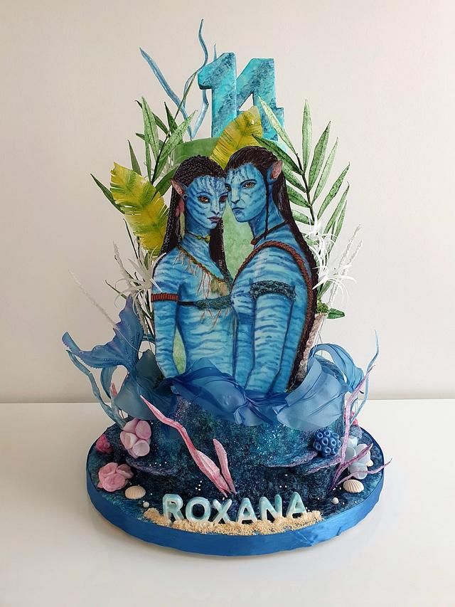 there is a blue cake with two people on it that says roxana in the middle