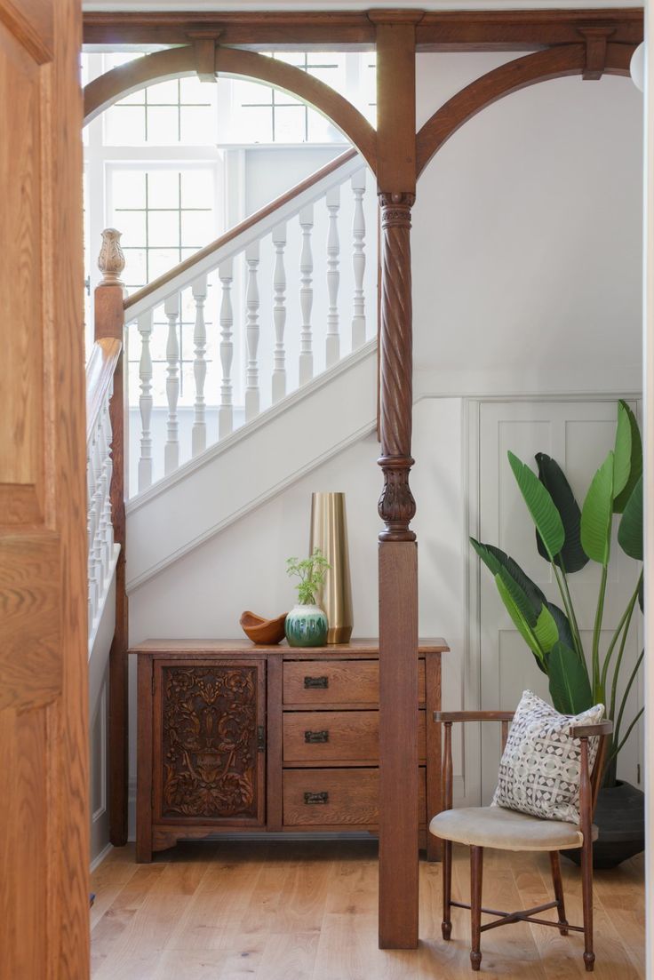 a living room with a couch and chair under a wooden structure next to a stair case