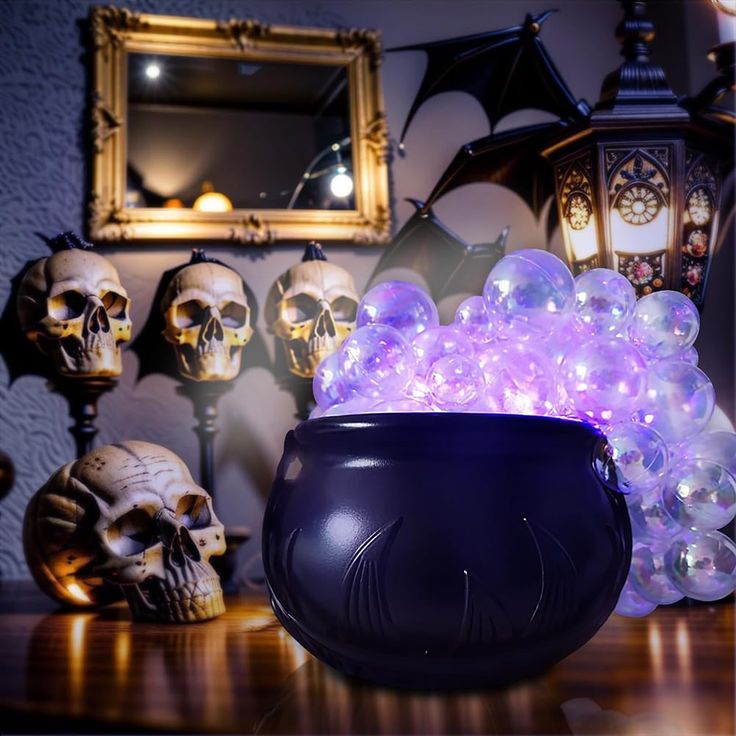 a bowl filled with crystal balls sitting on top of a wooden table next to skulls