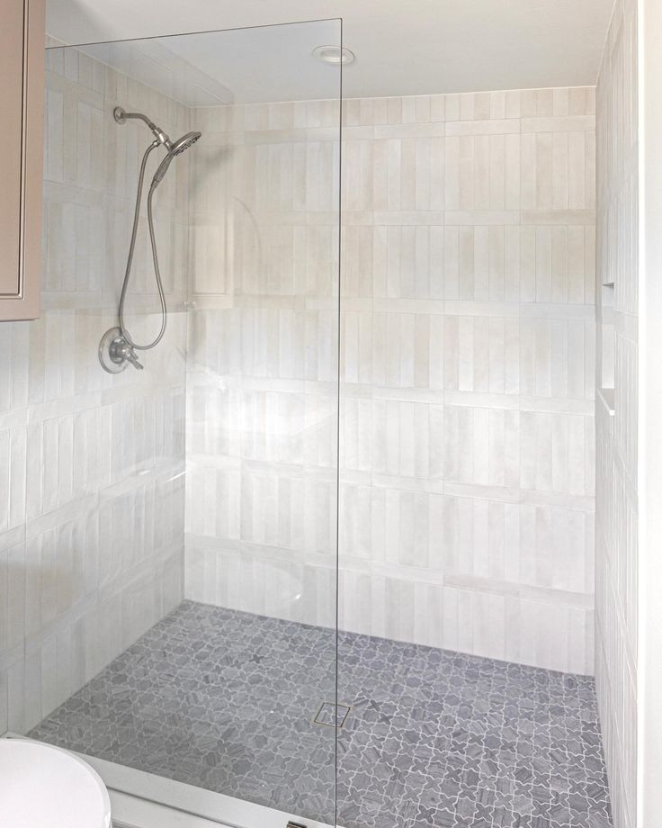 a walk in shower sitting next to a white sink and counter top under a faucet