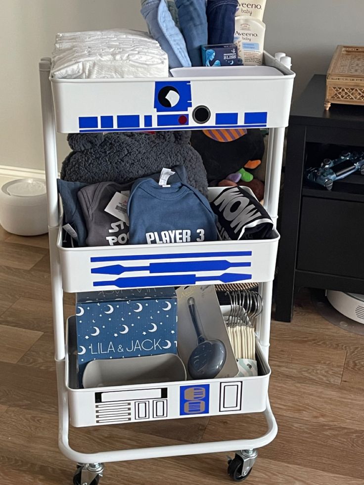 a white cart filled with clothes and other items on top of a hard wood floor