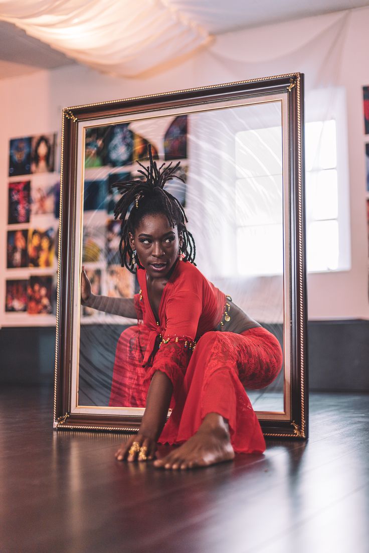 a woman sitting on the floor in front of a mirror