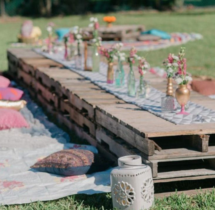 an outdoor picnic setting with flowers and candles on the table, along with other items