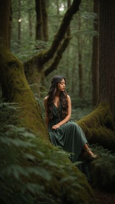 a woman is sitting on a mossy tree in the middle of a forest looking up into the sky