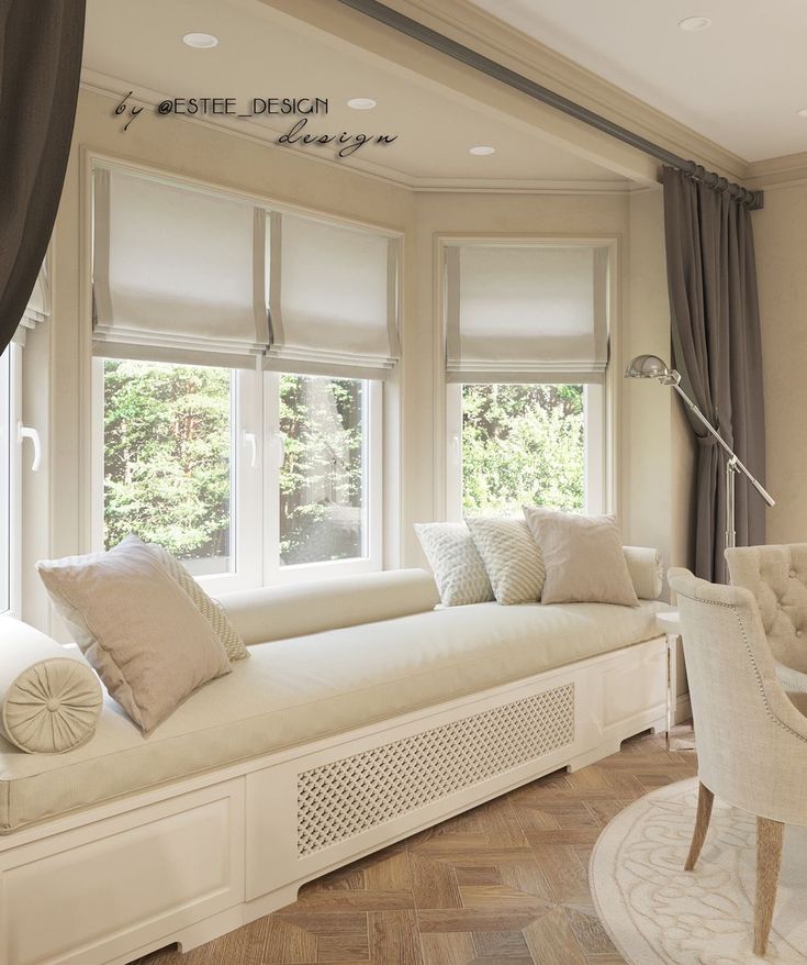 a living room filled with white furniture and lots of windows covered in shades on top of them