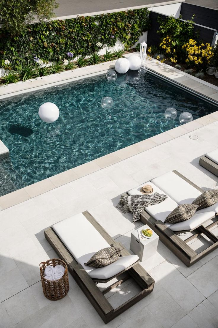 an outdoor swimming pool with lounge chairs around it