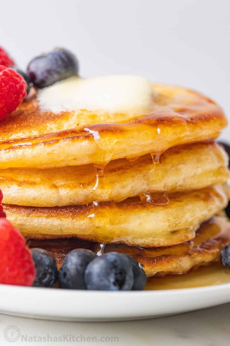 a stack of pancakes with syrup and berries