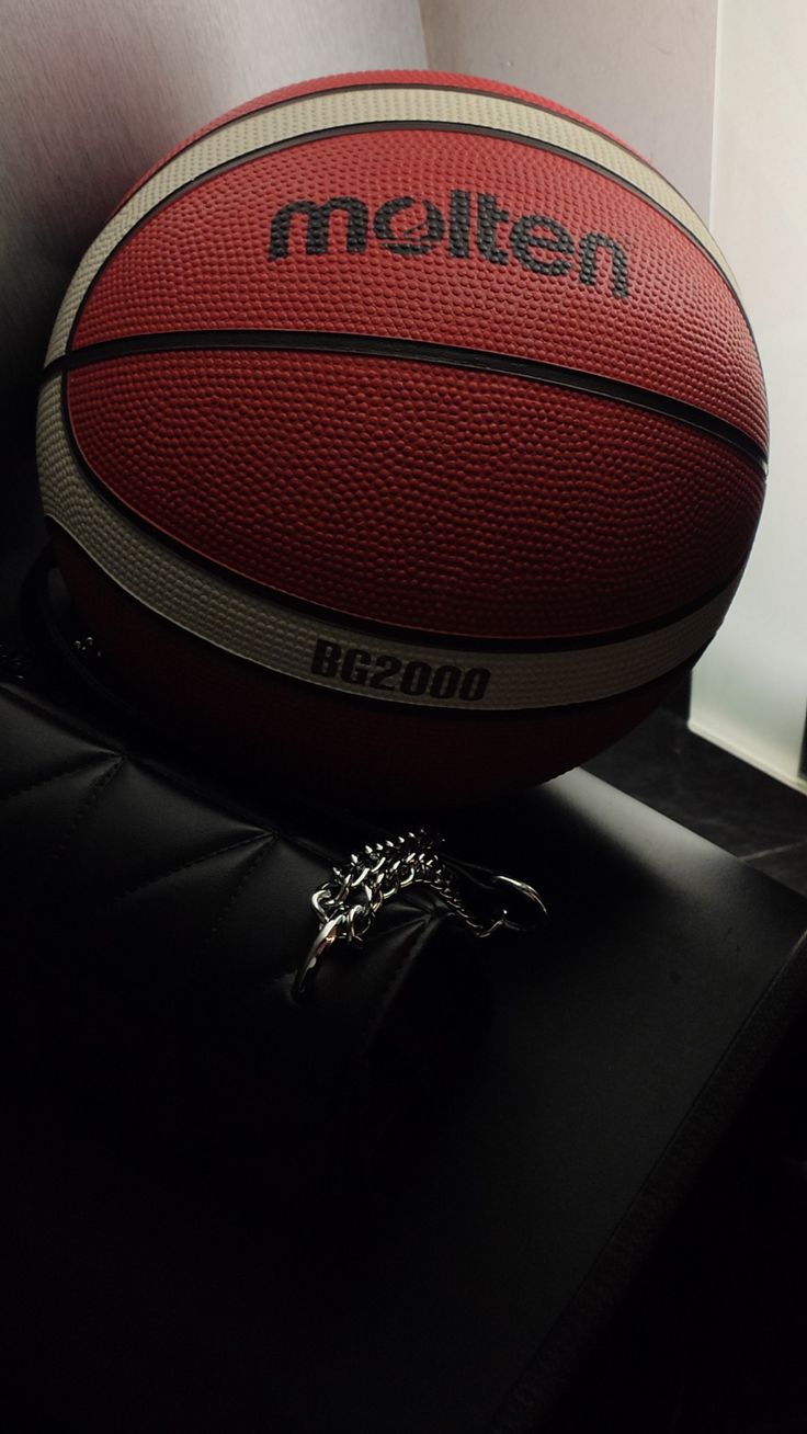 a red and white basketball sitting on top of a black table next to a keychain